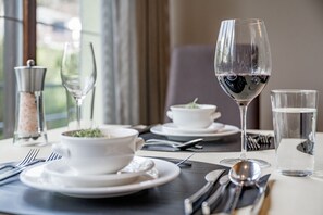 A dining table set with white plates, bowls, cutlery, and a wine glass. - Hotel zum Gourmet (Seefeld in Tirol)
