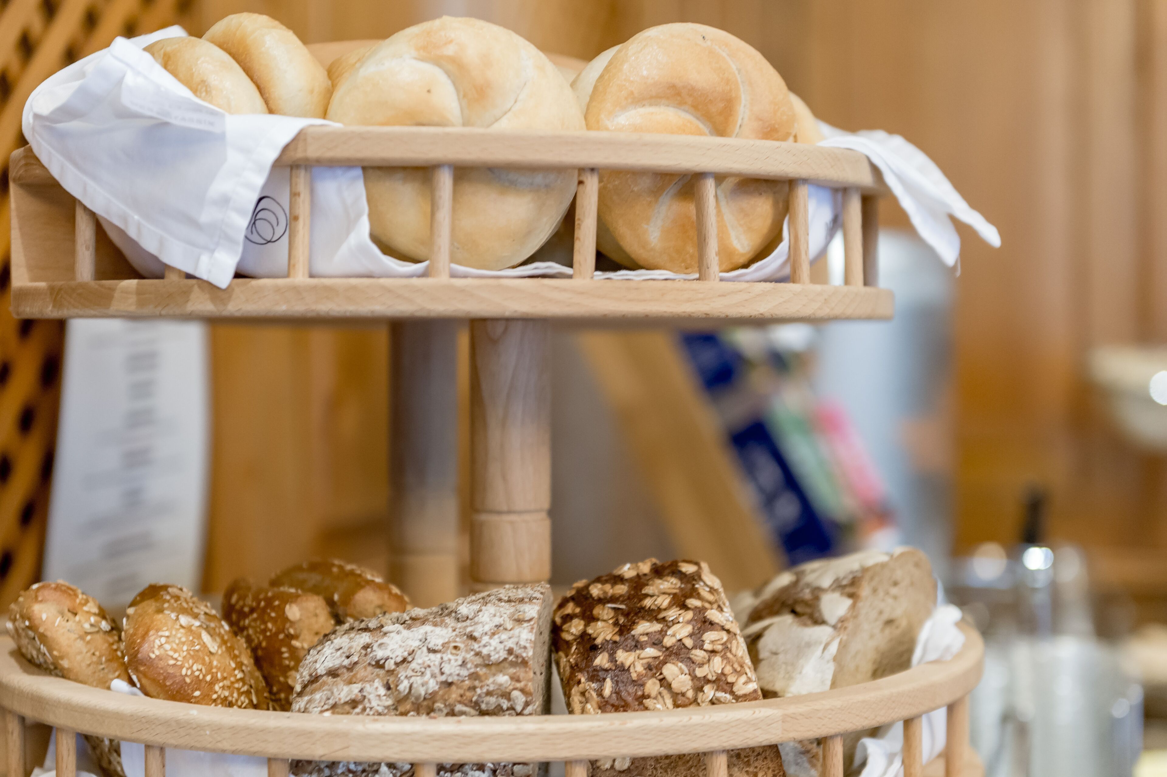 A wooden bread display with various types of bread, including rolls and loaves.