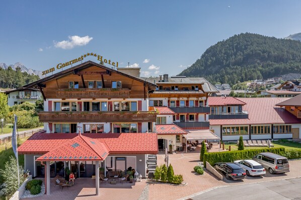A hotel with a red-tiled roof, a balcony with plants, and a sign reading "zum Gourmet Hotel". - Hotel zum Gourmet (Seefeld in Tirol)