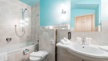 Un baño moderno con ducha de vidrio, inodoro y lavamanos con espejo.