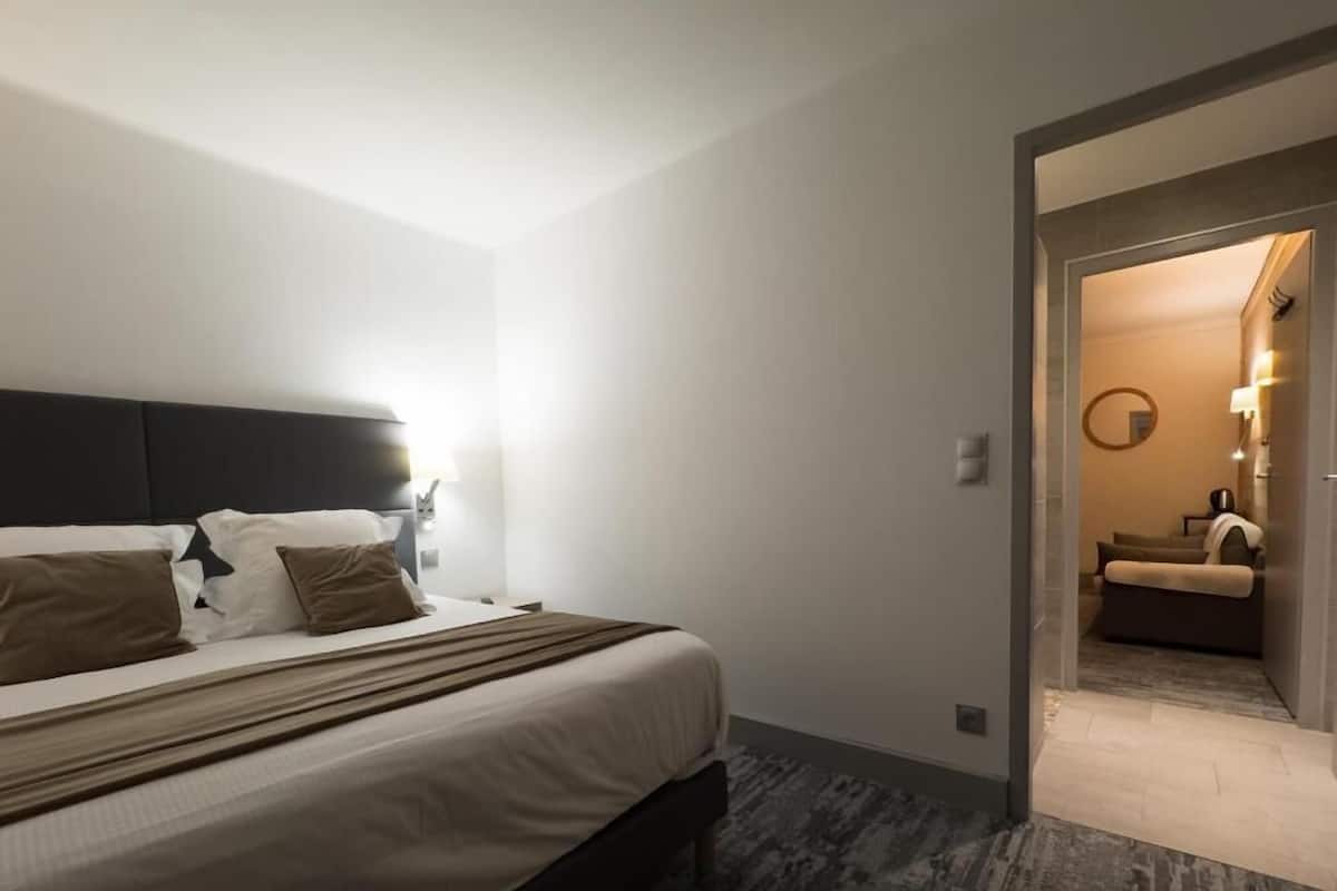 A hotel room with a bed, a nightstand, and a wall-mounted lamp.