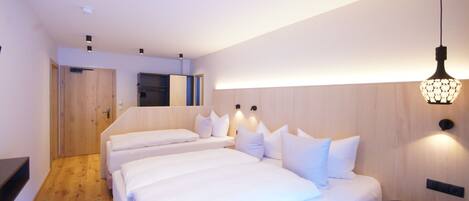 A hotel room with two beds, a small table, and a wooden floor.