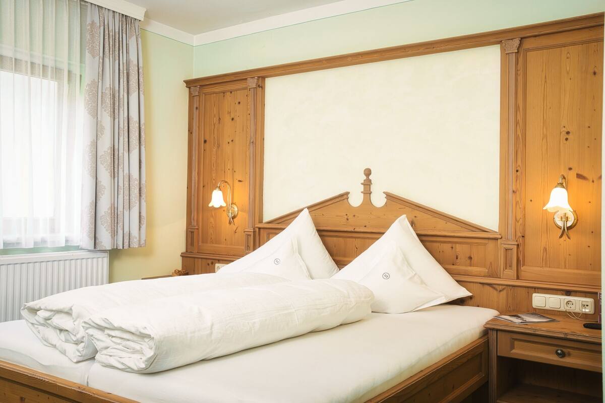 A neatly made bed with a wooden headboard, two bedside lamps, and a nightstand with a lamp.