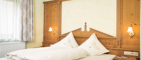 A neatly made bed with a wooden headboard, two bedside lamps, and a nightstand with a lamp.
