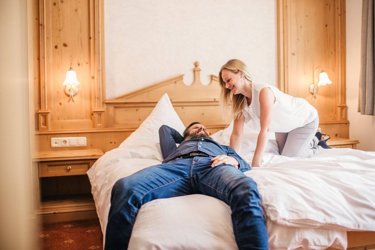 A hotel room with a wooden headboard, two bedside lamps, and a nightstand with a drawer.