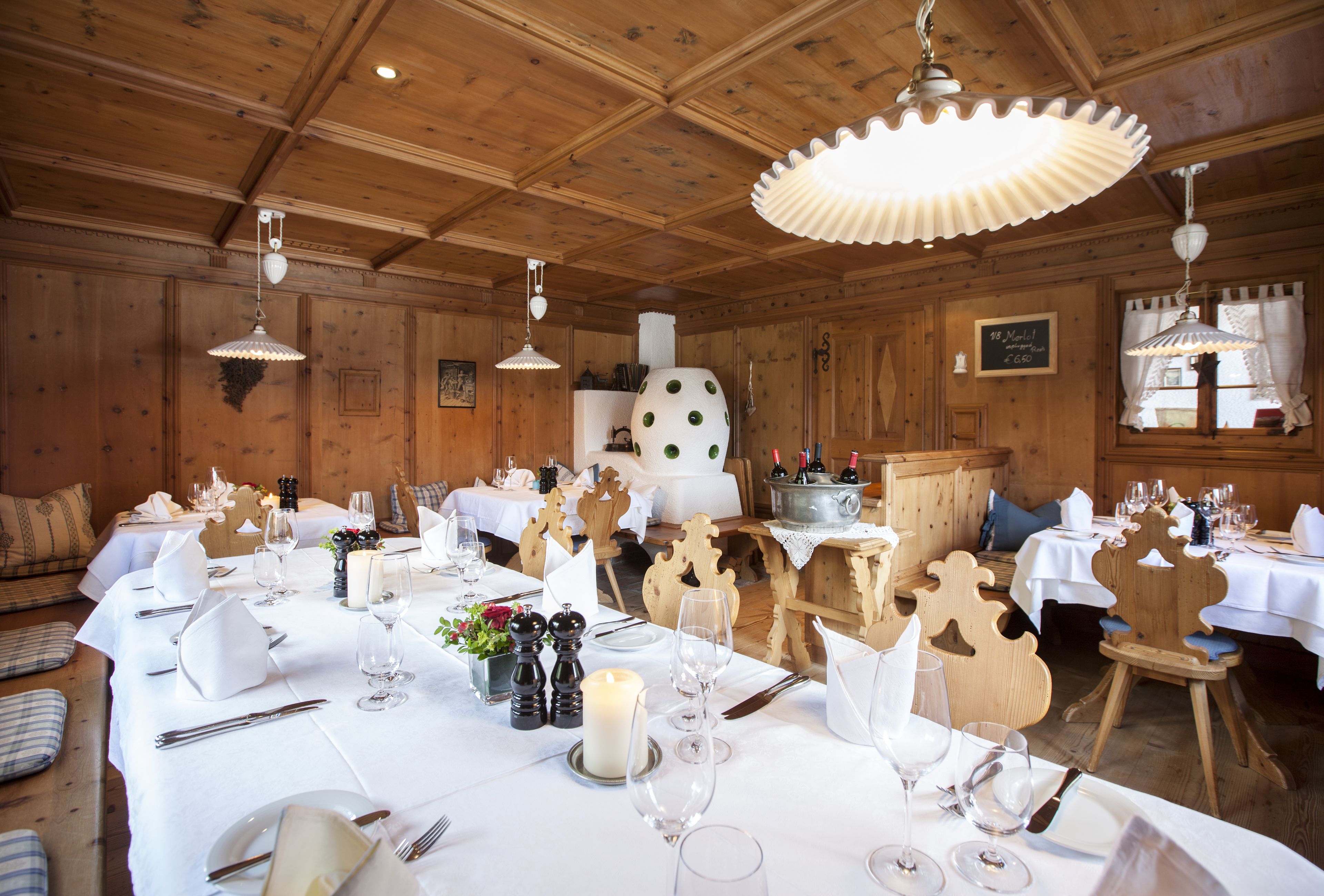 A restaurant with wooden interiors, white tablecloths, and candlelit tables.