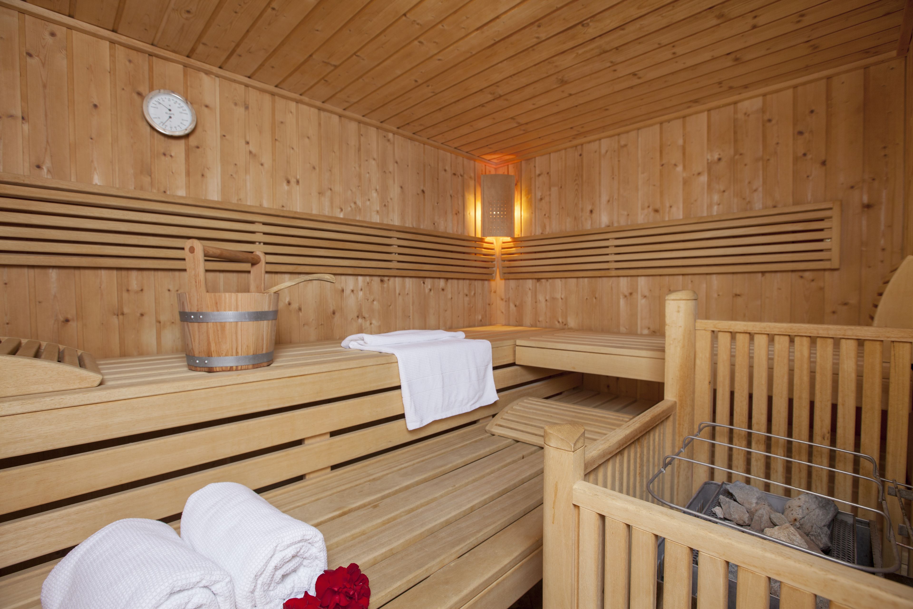 Una sauna de madera con bancos, un cubo y un perchero para toallas.