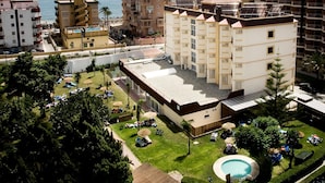 A multi-story hotel with a rooftop pool, surrounded by lush greenery and a view of the sea. - Hotel Monarque Cendrillón (Fuengirola)