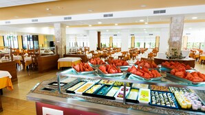 A buffet area with various food options and a seating area with tables and chairs. - Hotel Monarque Cendrillón (Fuengirola)