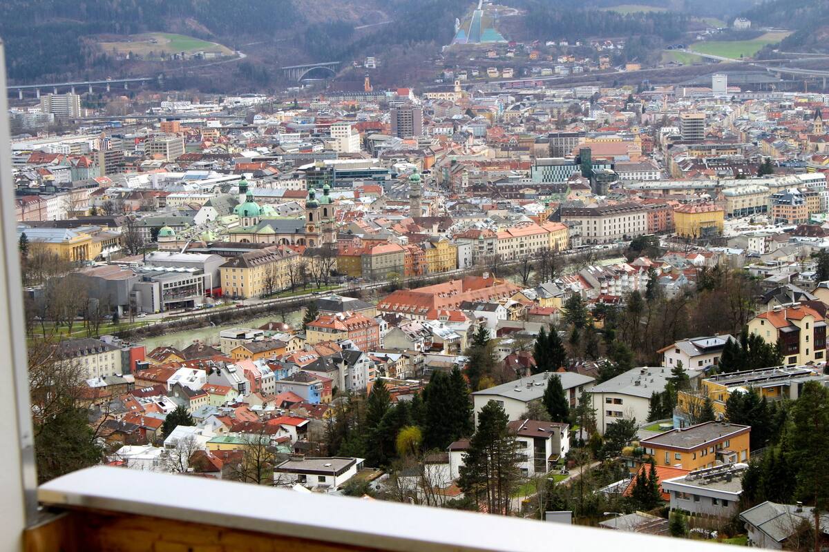 A panoramic view of a cityscape with a river running through it, various buildings, and a bridge in the distance.