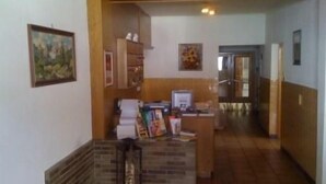 Un área de recepción con un mostrador, una computadora y una barra. Hay cuadros en la pared y un banco de madera.