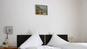 Ein Hotelzimmer mit zwei Betten, einem Bild an der Wand, einem Nachttischtelefon und einer Lampe auf dem Nachttisch.