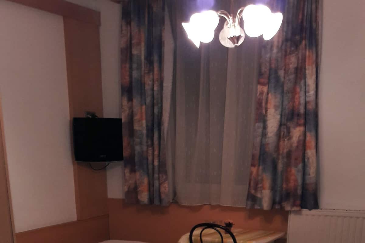 A hotel room with two single beds, a desk, a chair, and a television on the wall.