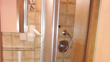 Un baño con lavamanos, espejo, ducha y un bote de basura.