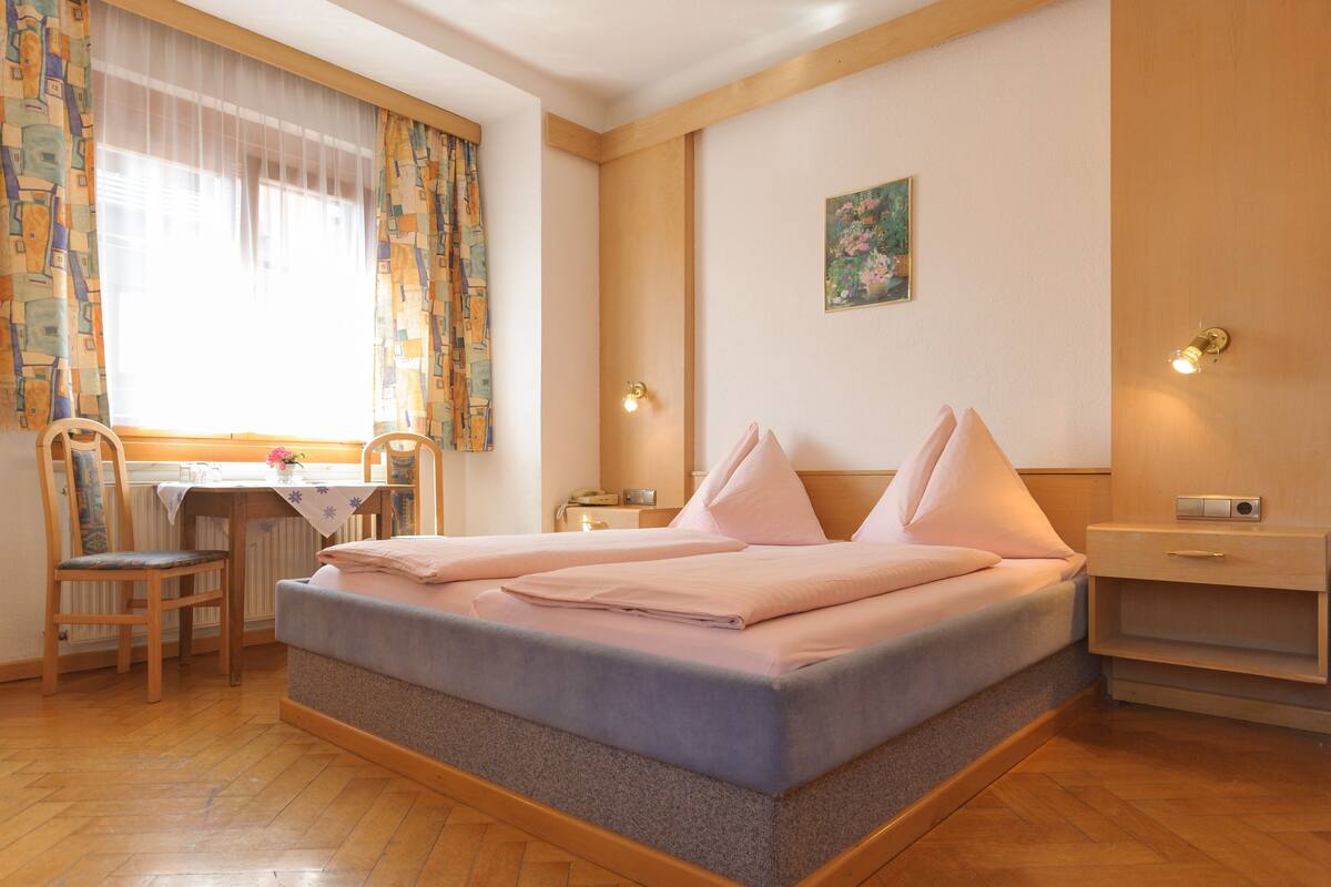 A neatly arranged bedroom with a bed, a desk, and a chair.