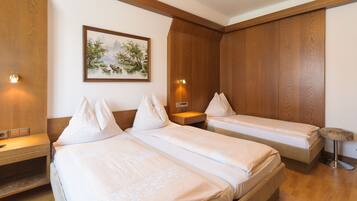 A hotel room with two beds, wooden paneling, a painting on the wall, and bedside lamps.