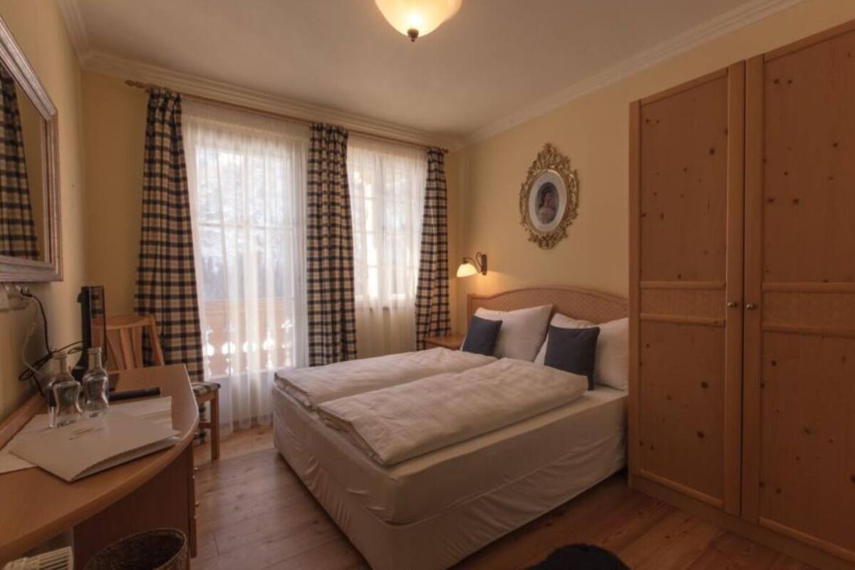 Una cama doble con cabecera, un escritorio con silla, una lámpara y un armario.