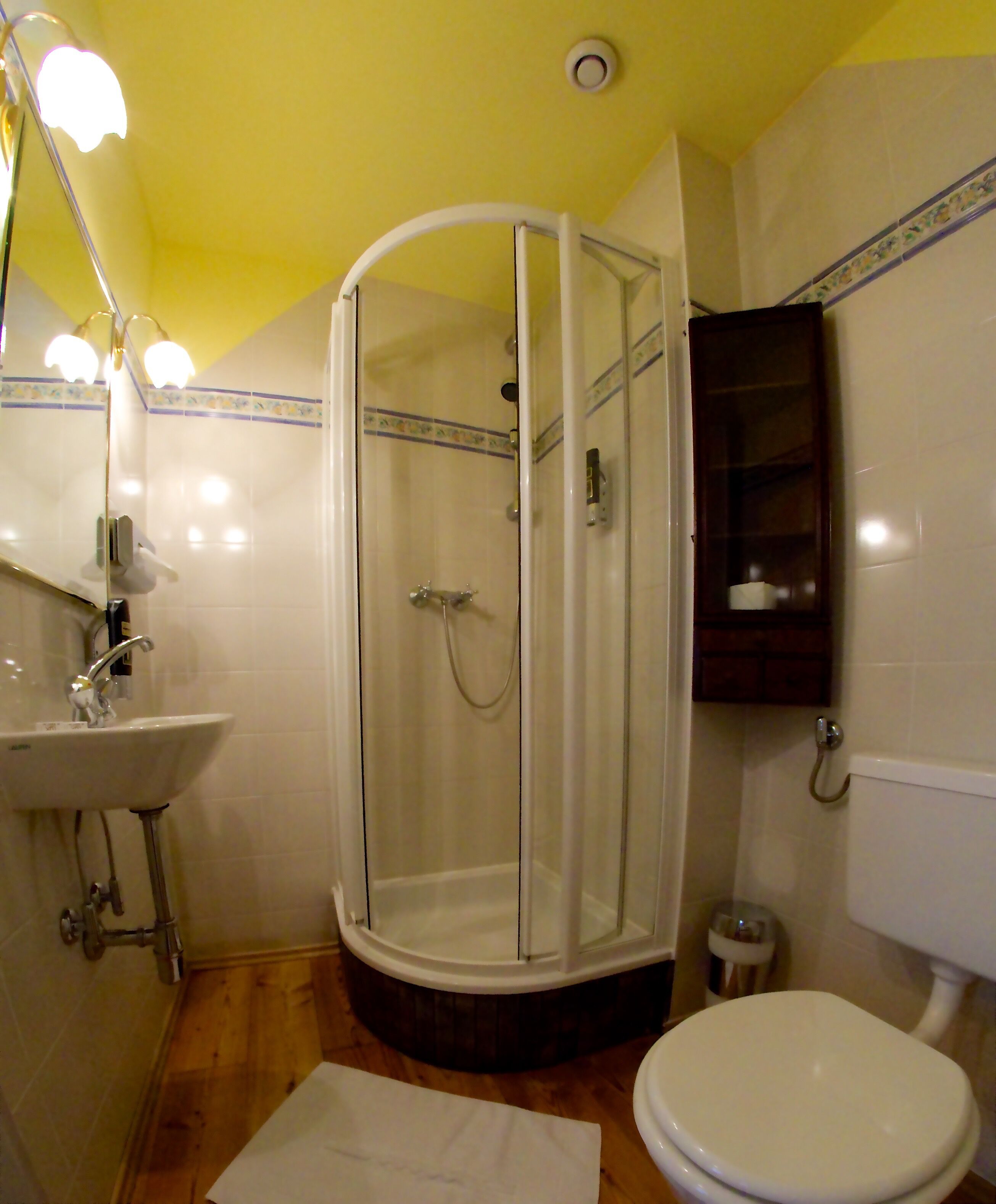 A bathroom with a shower, sink, toilet, and a mirror with lights.