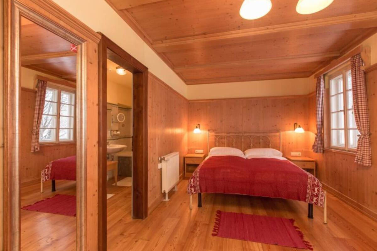 Un dormitorio con paneles de madera, una cama, dos lámparas de noche y un espejo.