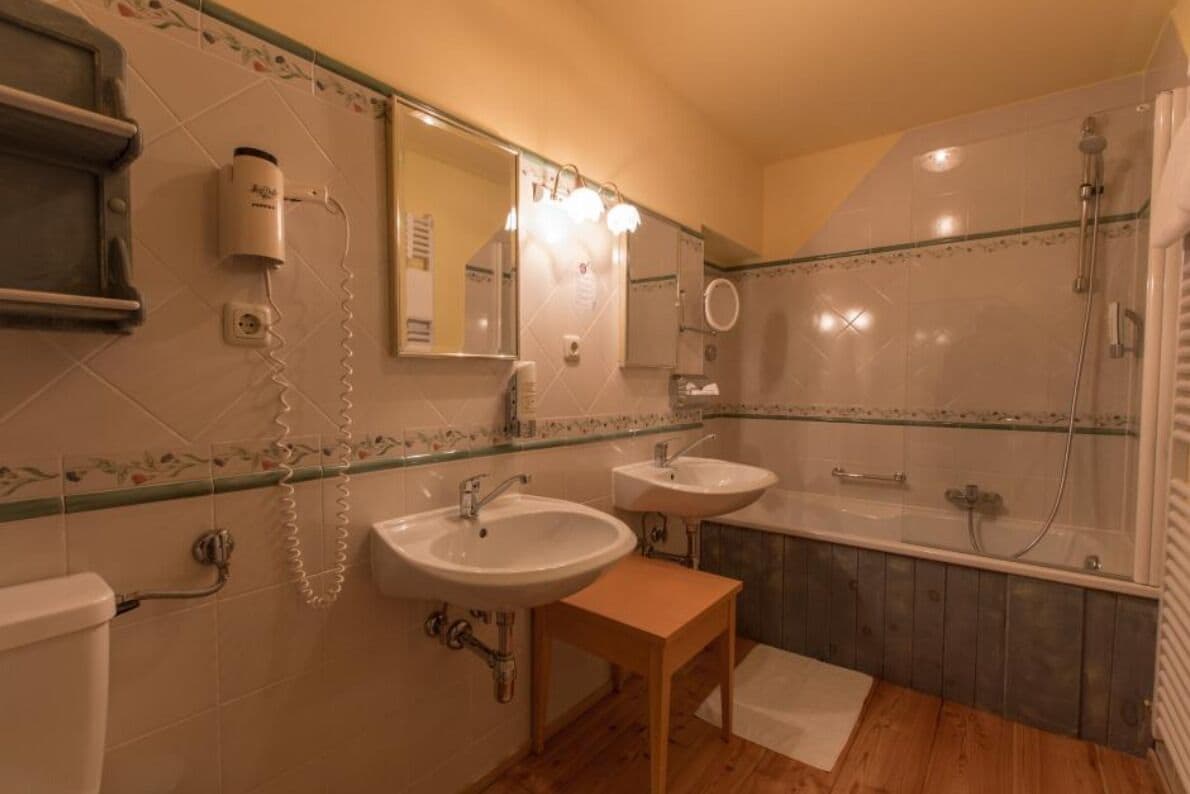 A bathroom with two sinks, a mirror, a hairdryer, and a shower.