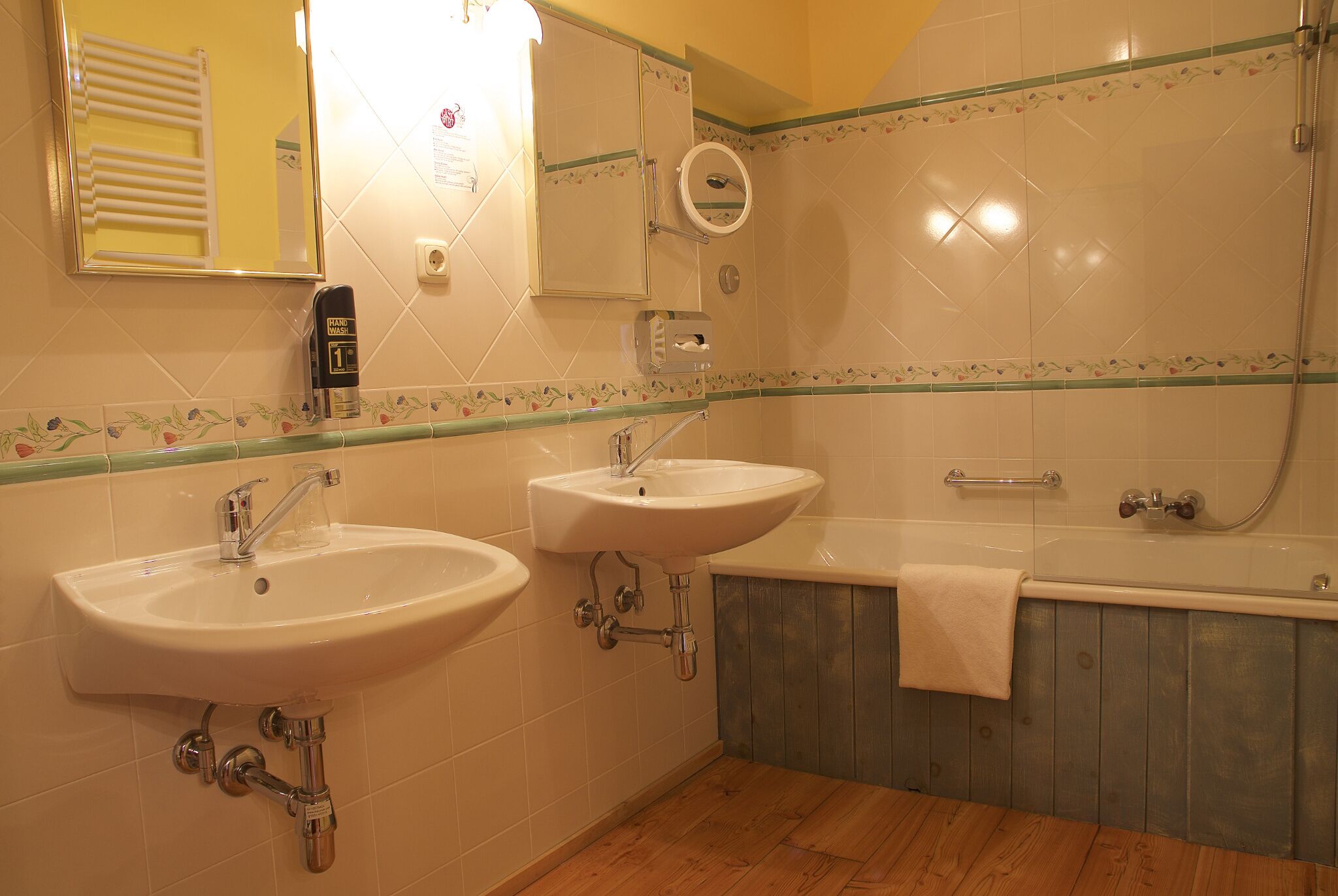 Un baño con dos lavamanos, un espejo, un perchero para toallas y una bañera.