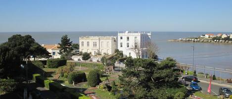A large white building with a symmetrical facade, situated near a body of water.