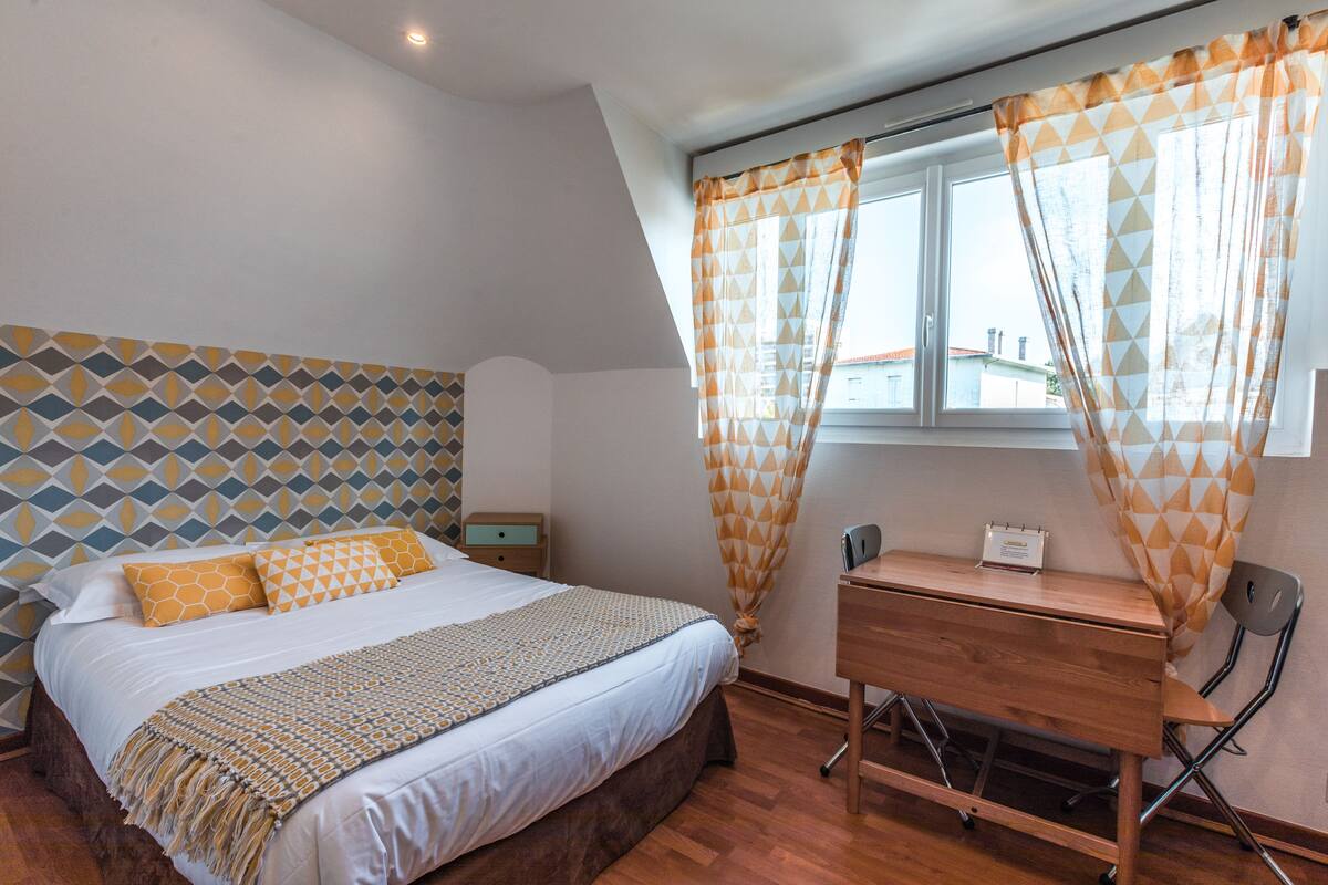 Um quarto com uma cama, uma escrivaninha e uma cadeira.