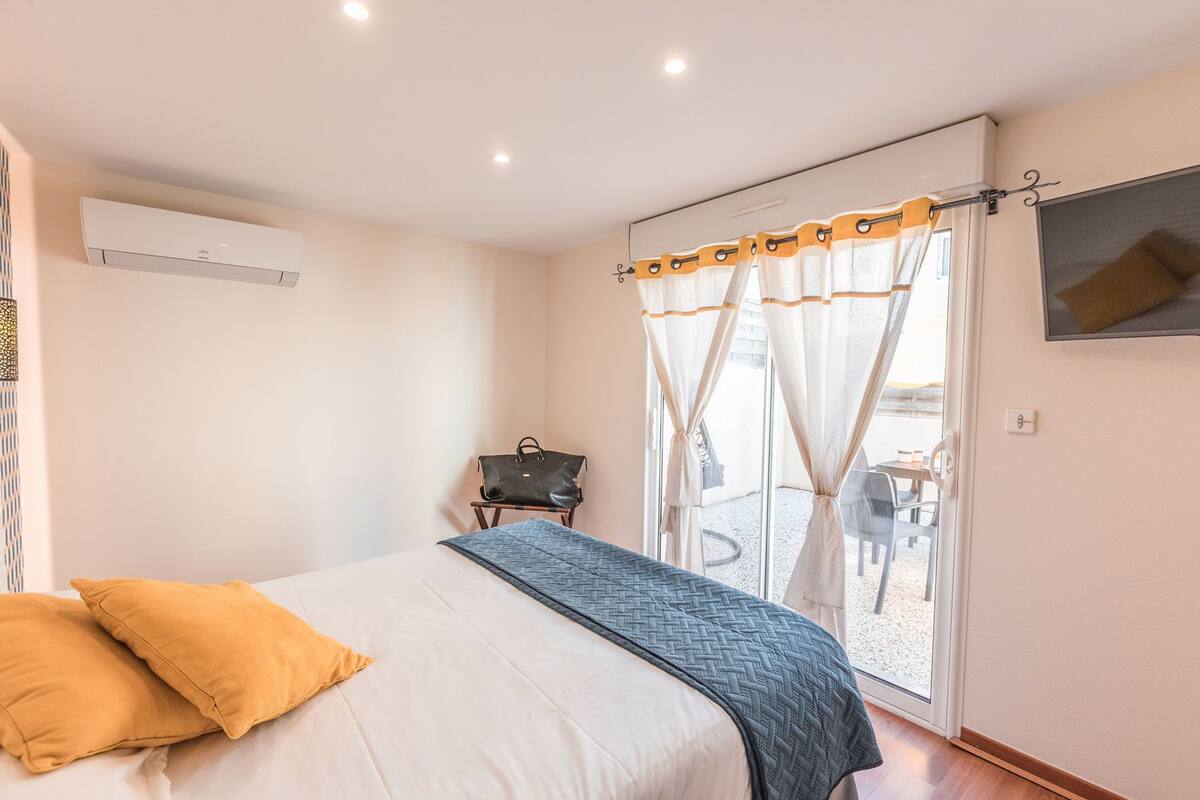 Quarto com uma cama, uma mala e uma janela com cortinas.