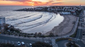 Une ville côtière avec une plage, une route et un bâtiment doté d’une tour.