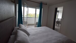 A hotel room with a large bed, a sliding glass door leading to a balcony, and a view of the outside. - Appart Hotel Beau Rivage (Royan)