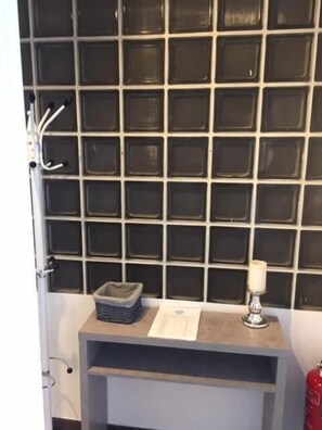 Una habitación con pared de azulejos, una mesita con una vela y un extintor.