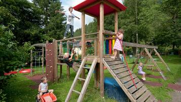Children can play and climb on the structure's slide and climbing elements in this park setting.