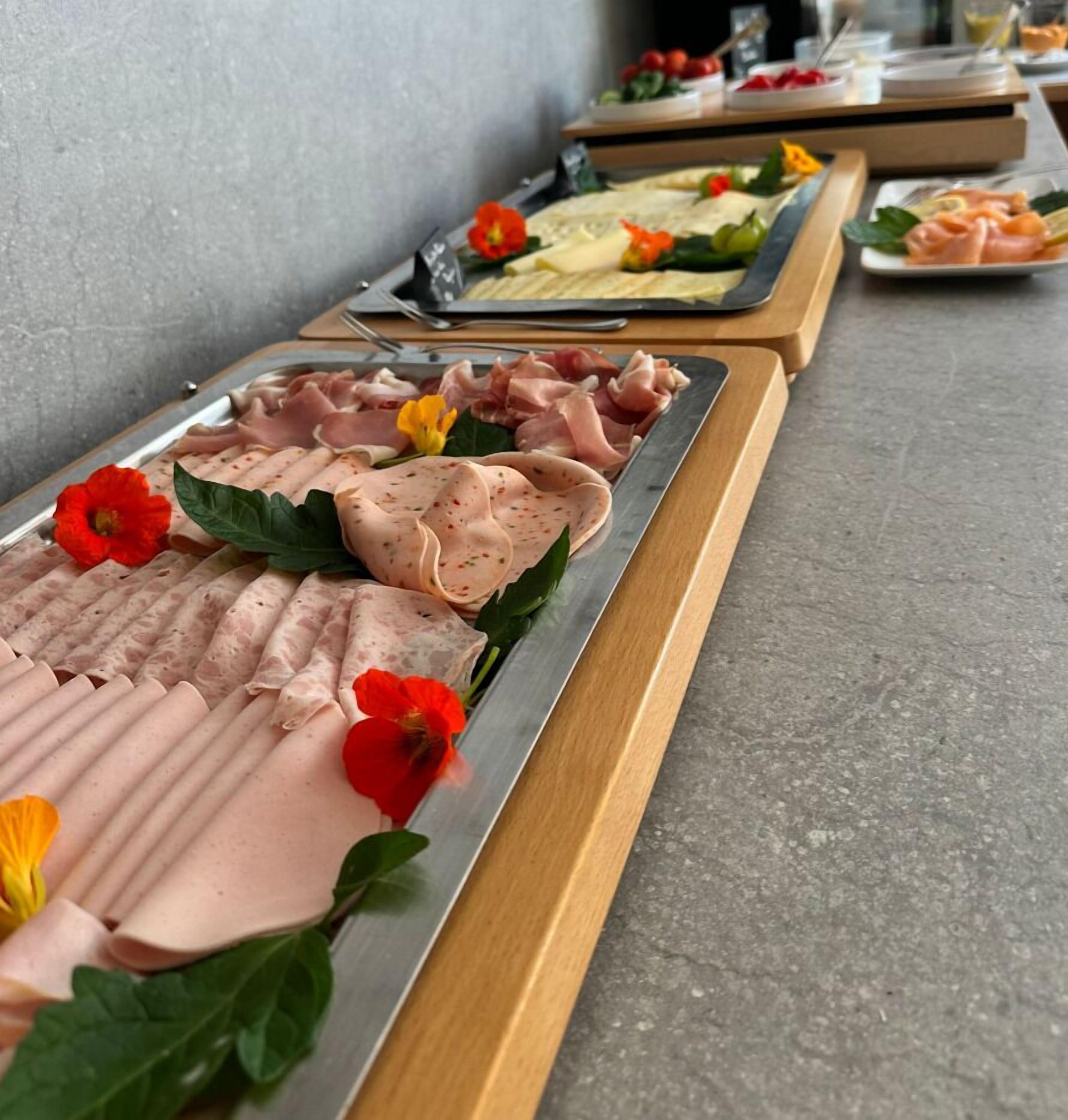 Un bufé con diversas fuentes de carne y queso, decorado con flores.