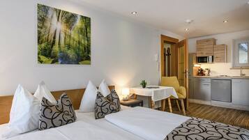 A hotel room with a bed, a desk, a chair, a small table, a microwave, and a cabinet.