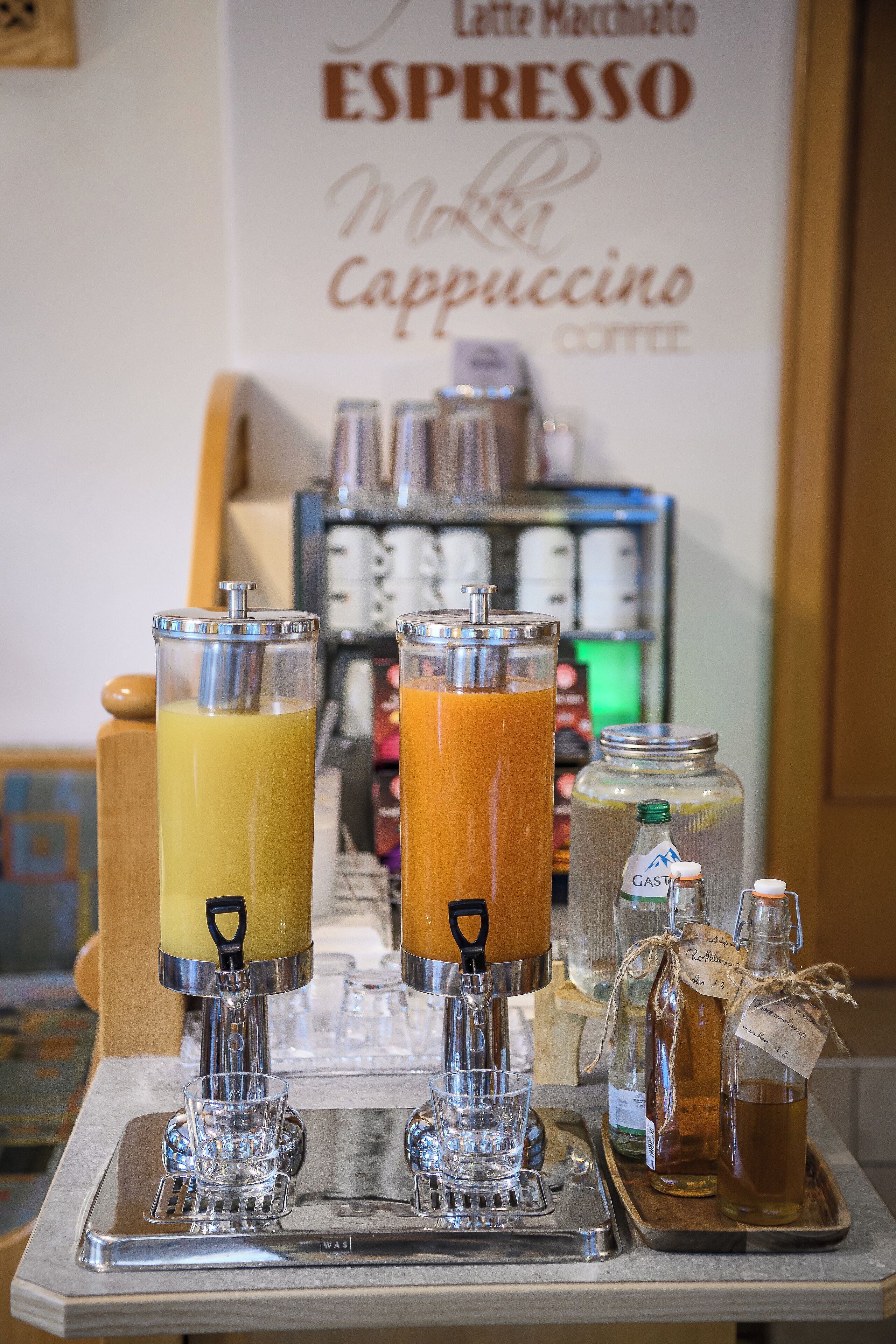 Una estación de barista con dos máquinas de espresso y una bandeja con vasos y botellas.