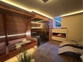 Ein moderner Spa-Bereich mit einer Holzbank, einer Glast sauna und einem Kamin.