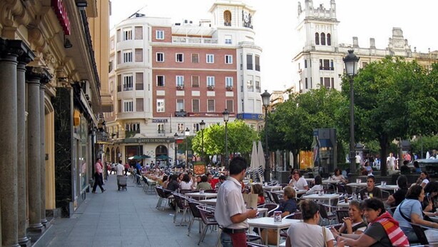An outdoor cafe with tables and chairs, surrounded by buildings with classical architecture. - Boston (CORDOBA)