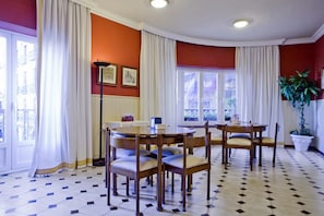 A dining area with a round table and chairs, large windows with curtains, and a tiled floor. - Boston (CORDOBA)