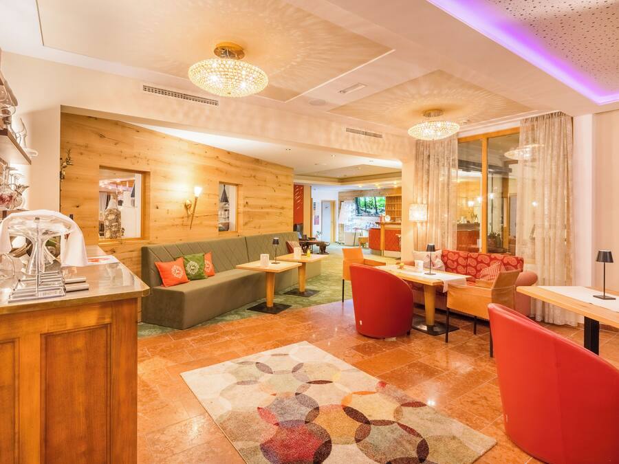 Un lobby moderno de hotel con mostrador de recepción de madera, zonas de estar y vistas al comedor.