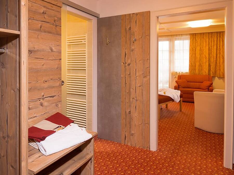 Ein Hotelzimmer mit einem Holzschrank, einem Bett mit roter und weißer Decke, einer Couch und einem gemusterten Teppich.