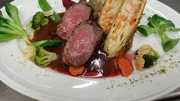 A white plate with a steak, vegetables, and a breaded item.