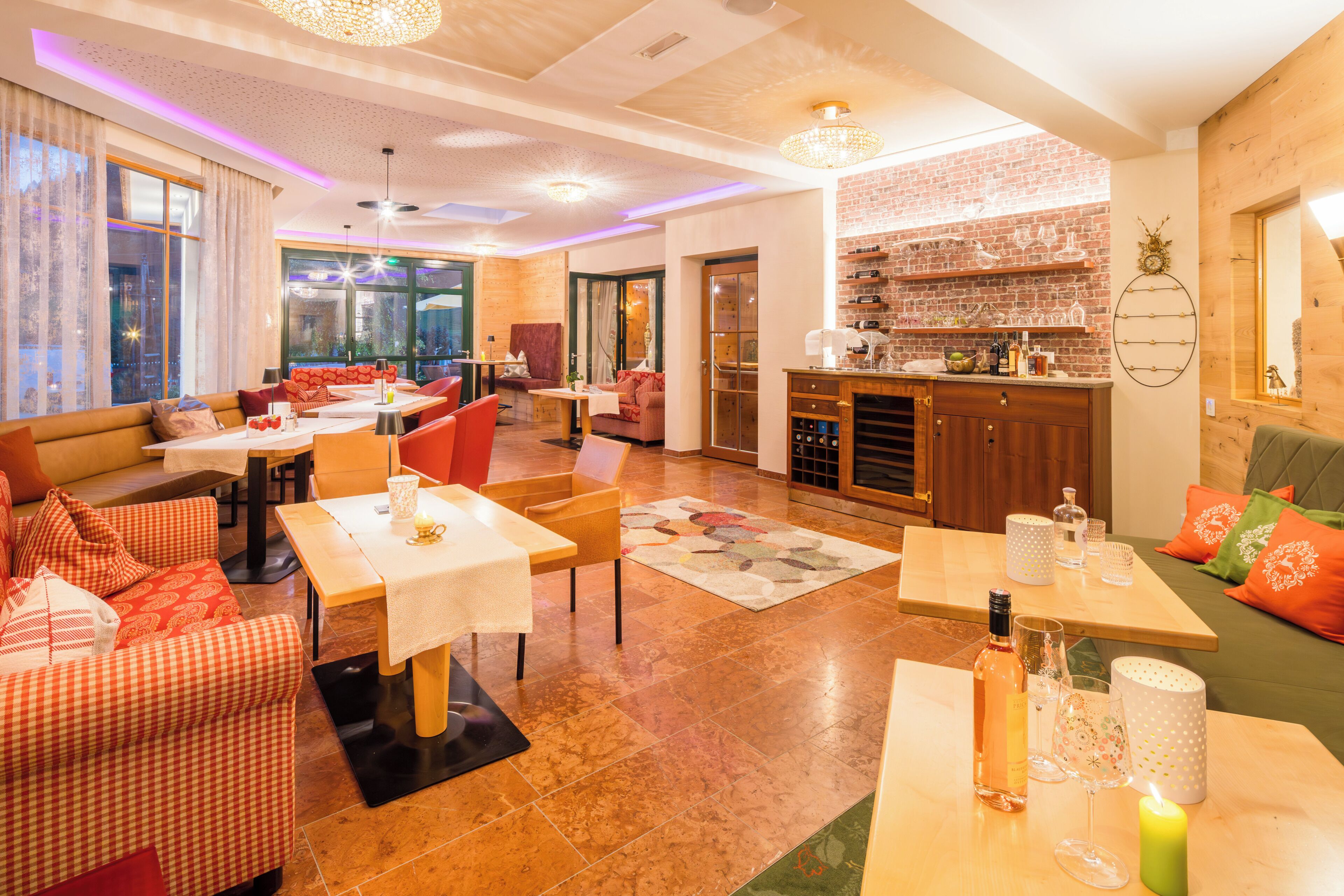 A modern hotel room with a dining area, kitchen, and large windows.
