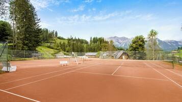 Una cancha de tenis con red, bancos y una valla.