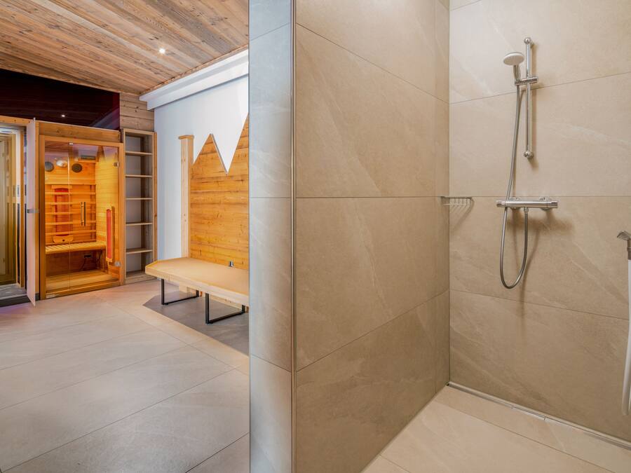 Un baño moderno con ducha, banco y zona de sauna.