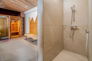 Une salle de bain moderne équipée d’une douche, d’un banc et d’un espace sauna.