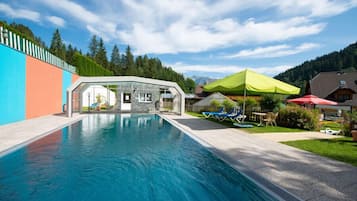 Relax by the pool surrounded by lush greenery and a serene mountain backdrop.