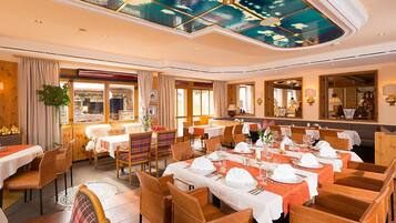 Un restaurant amb diverses taules preparades per dinar, amb un sostre decorat amb un disseny que imita un cel.