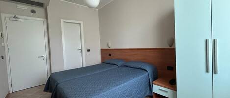 A bedroom with a bed, a wardrobe, a desk, and a chair.