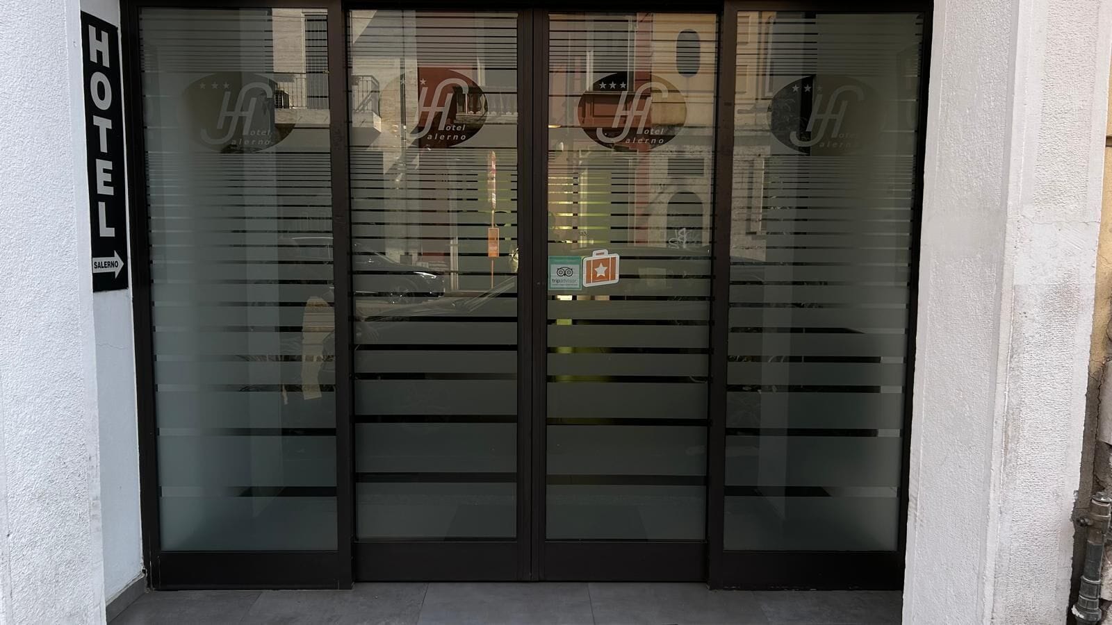 A hotel entrance with frosted glass doors and a sign indicating the hotel name.