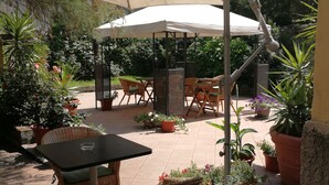An outdoor patio with wicker furniture, a table, and potted plants. - Hotel Salerno (Milan)